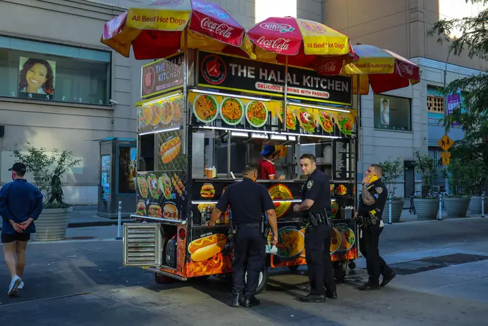 NYPD officers order food from a street cart.